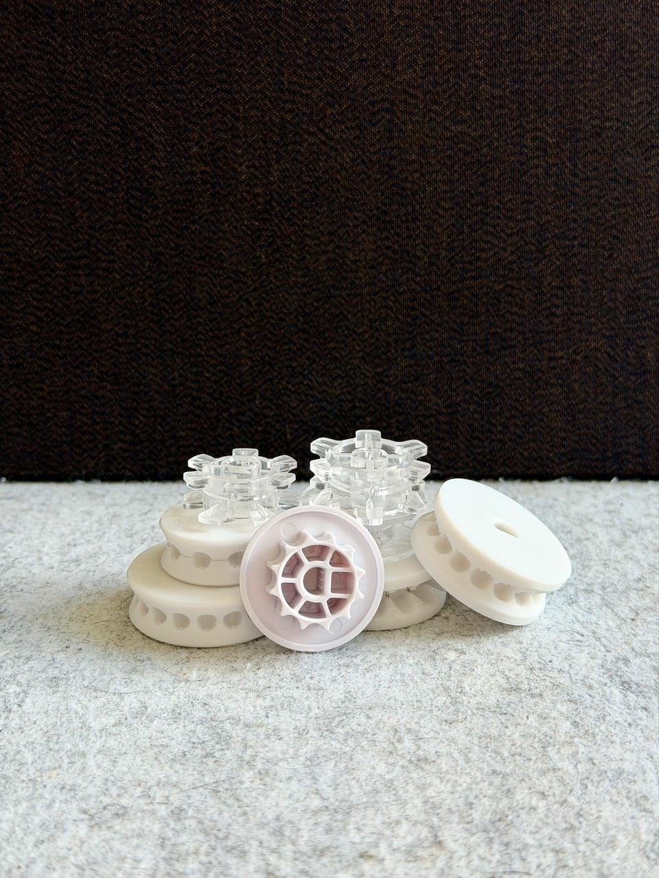 Several white and clear 3D-printed gear parts with toothed edges, arranged on a table.